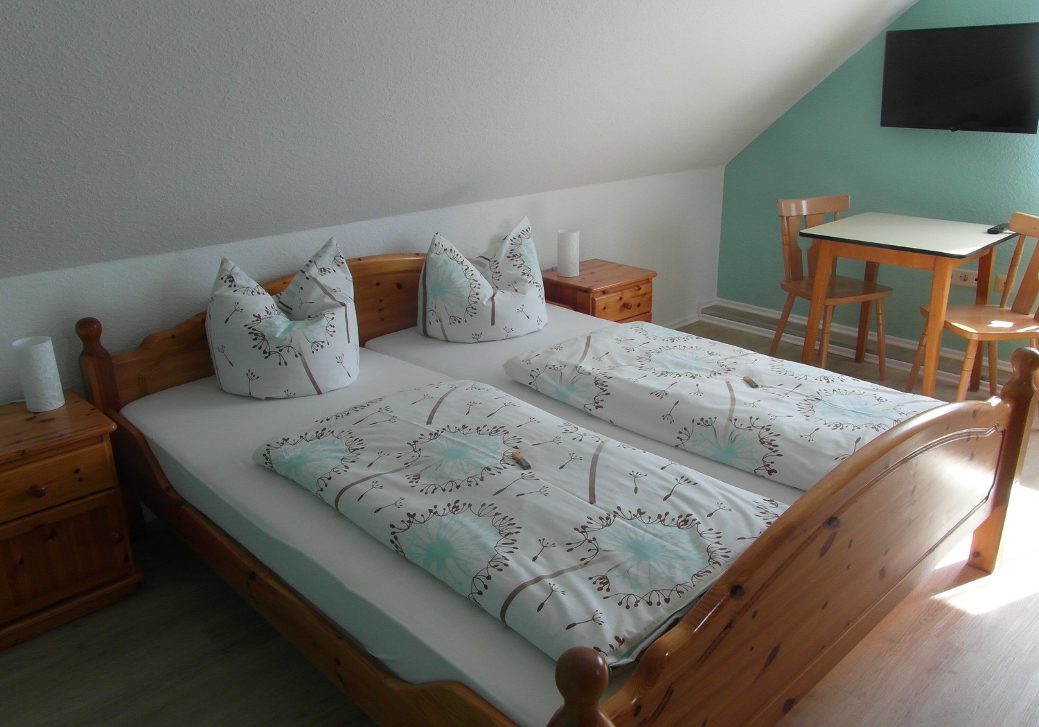 Helles Doppelzimmer mit zwei Betten, TV und kleinem Sitzbereich