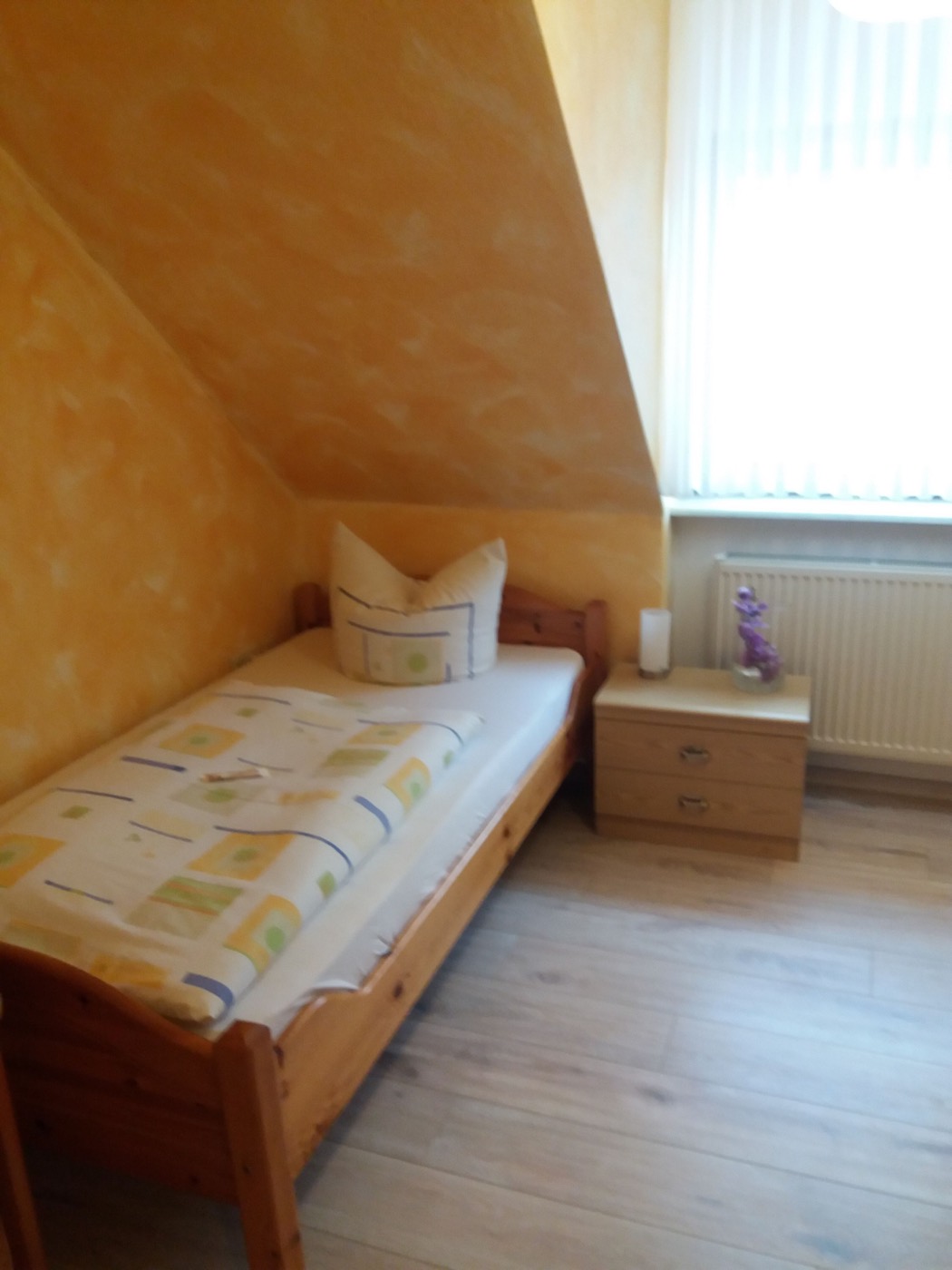 Gemütliches Einzelzimmer mit Kiefernbett und warmer Wandgestaltung